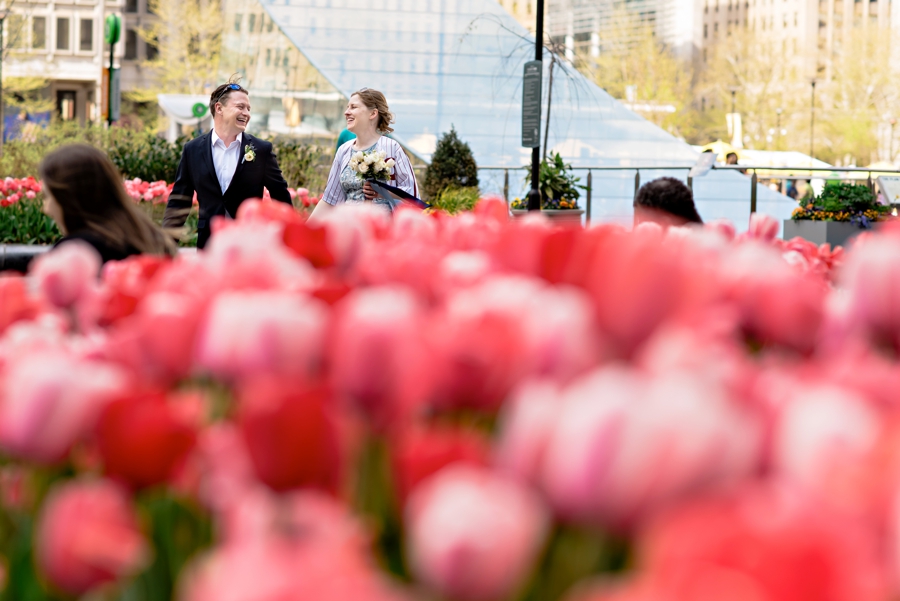 A wedding couple run in between the tulips outside of city hall in Philadelphia.